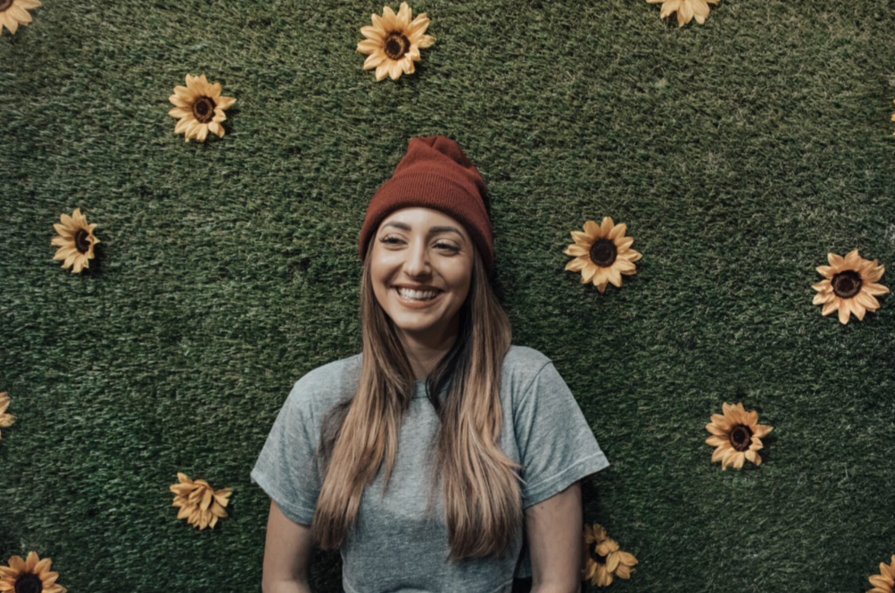 Woman standing in front of a wall of greenery and flowers.